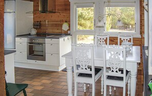 A kitchen with white cabinetry, a stove, and a dining table with chairs. - Amazing home in Rømø with kitchen (Rømø)
