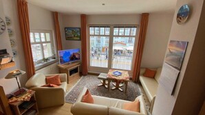 A cozy living room with a television, sofa, and a small table. - (269) 3- room apartment - apartment house Strandburg (Kühlungsborn)