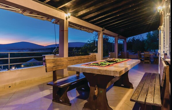 An outdoor patio with a table, benches, and a view of the landscape.