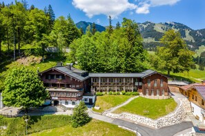 Ein großes Chalet mit mehreren Gebäuden, umgeben von üppiger Vegetation und Bergen.
