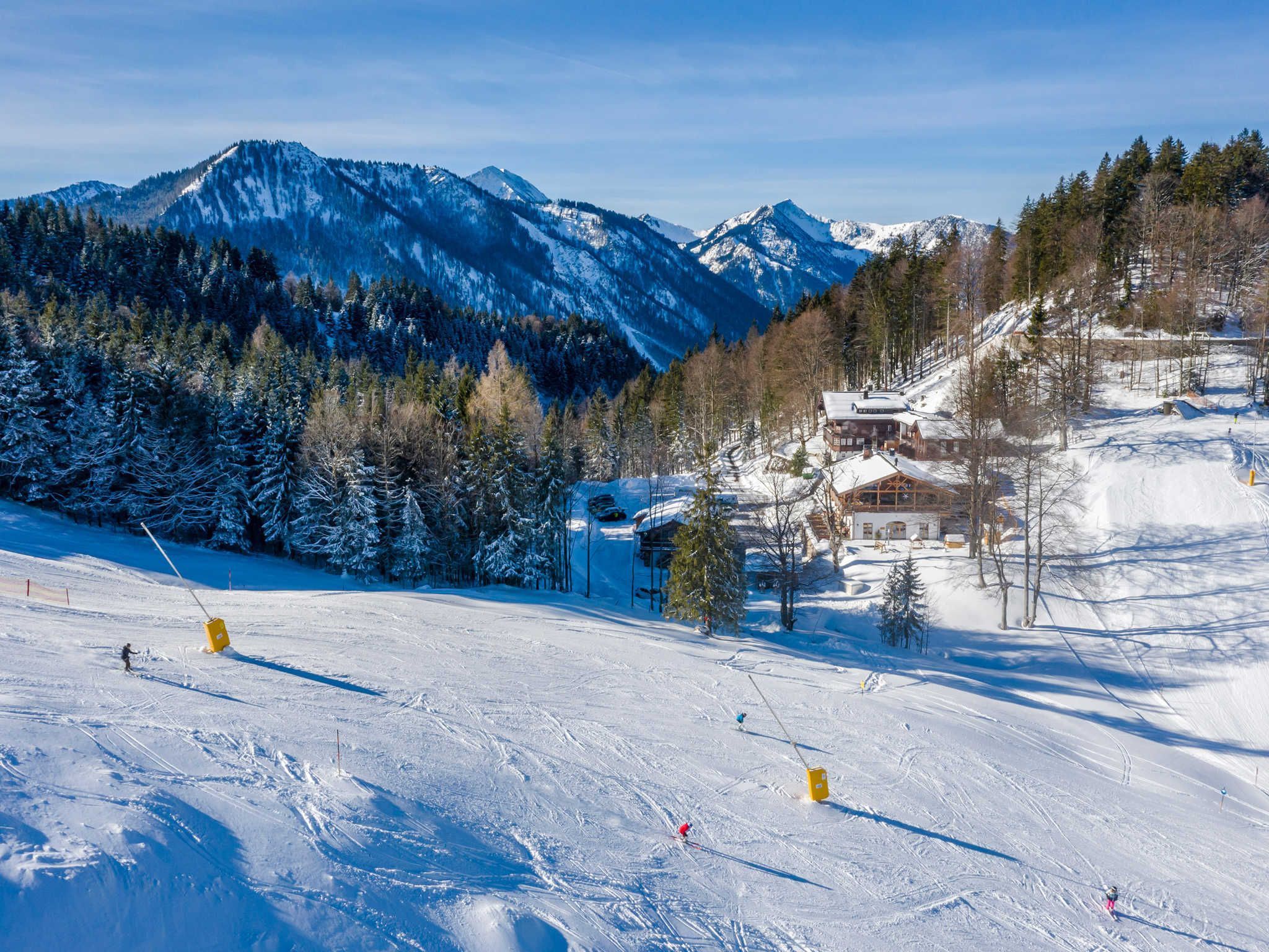 Une station de ski avec une montagne en toile de fond, un chalet et une piste enneigée.