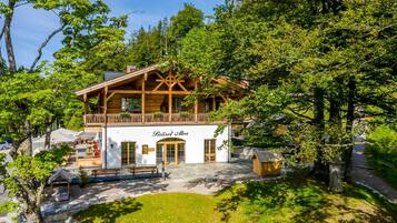 Ein Chalet mit Balkon, einem Schild mit der Aufschrift 'Bräu Alm' und einem steinbelagten Weg zum Eingang.