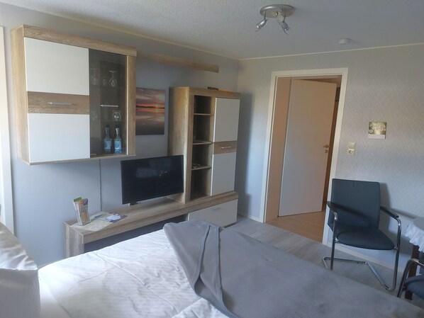 Habitación de hotel con cama, televisión, escritorio con computadora, silla y armario.