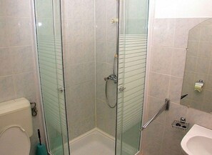 Ett badrum med en dusch som är avskärmad med glasväggar, en toalett och ett handfat.