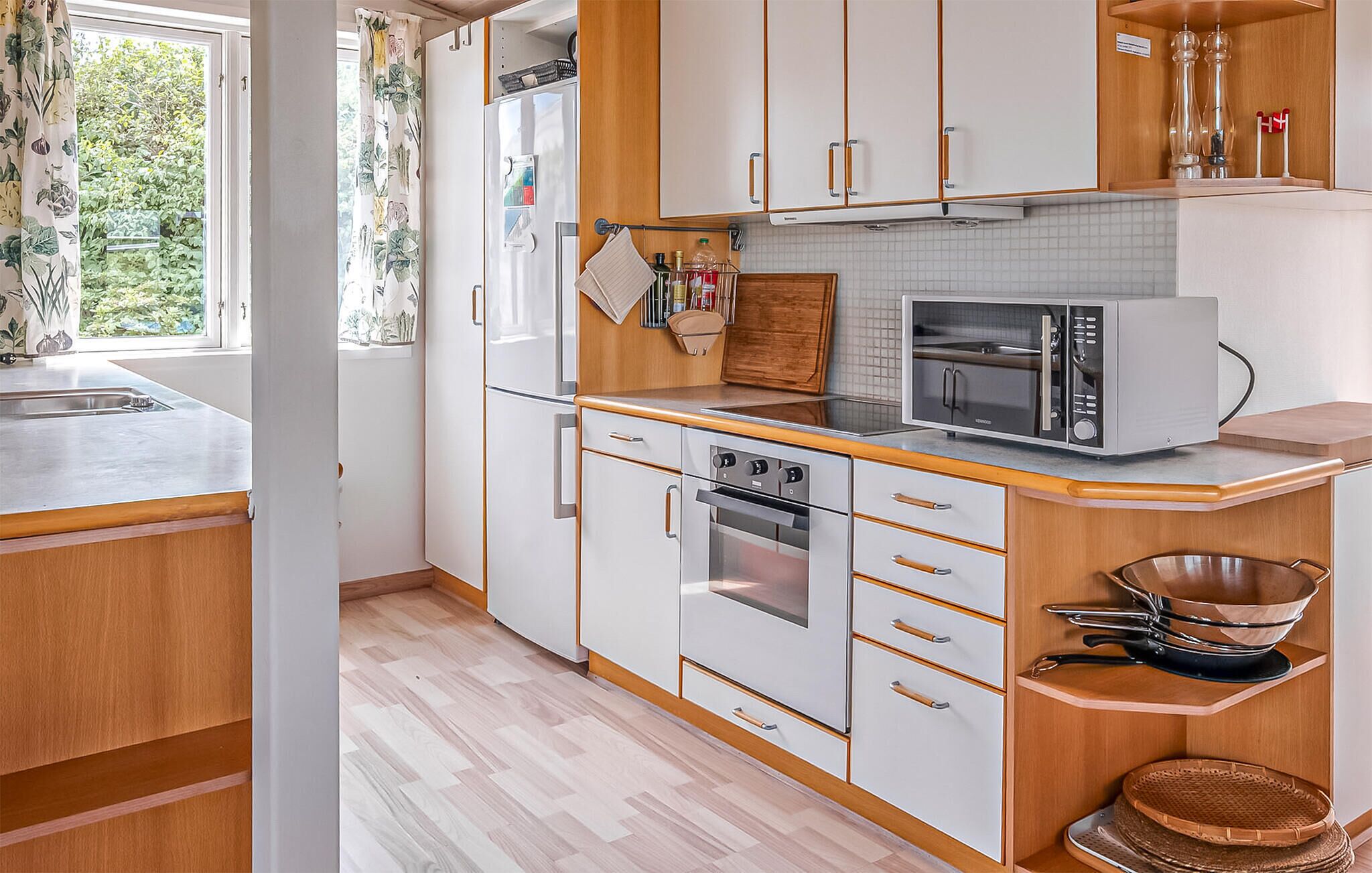 Una cocina compacta con armarios blancos, microondas, horno y pileta.