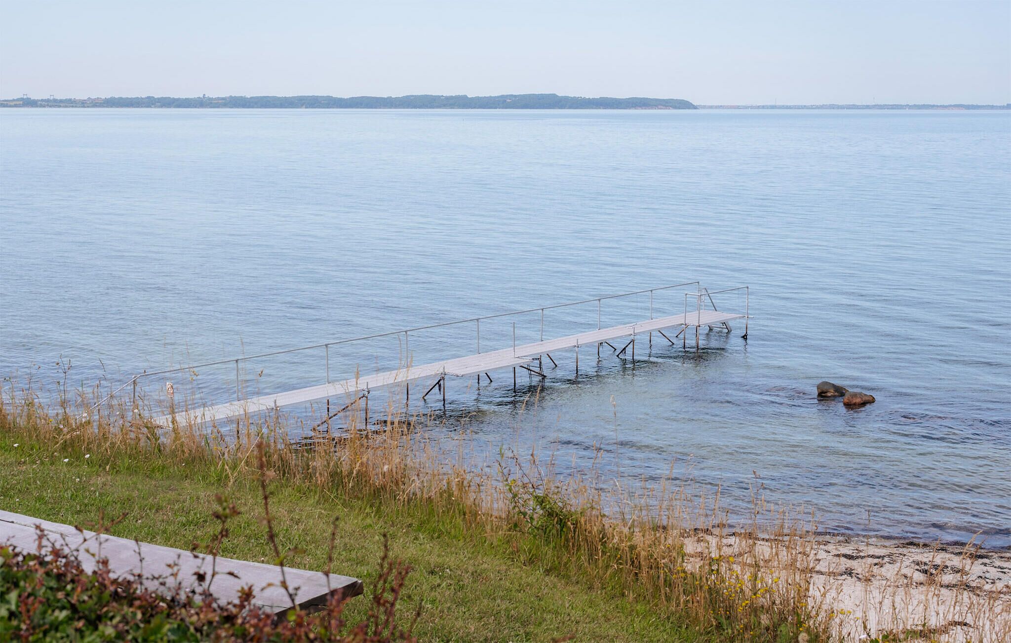 Ein ruhiger See mit einem hölzernen Steg, der sich ins Wasser erstreckt.
