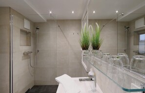 A modern bathroom with a glass shower enclosure, a glass-topped vanity, and a large mirror.