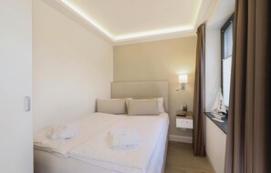 A hotel room with a bed, bedside table, lamp, and curtains.