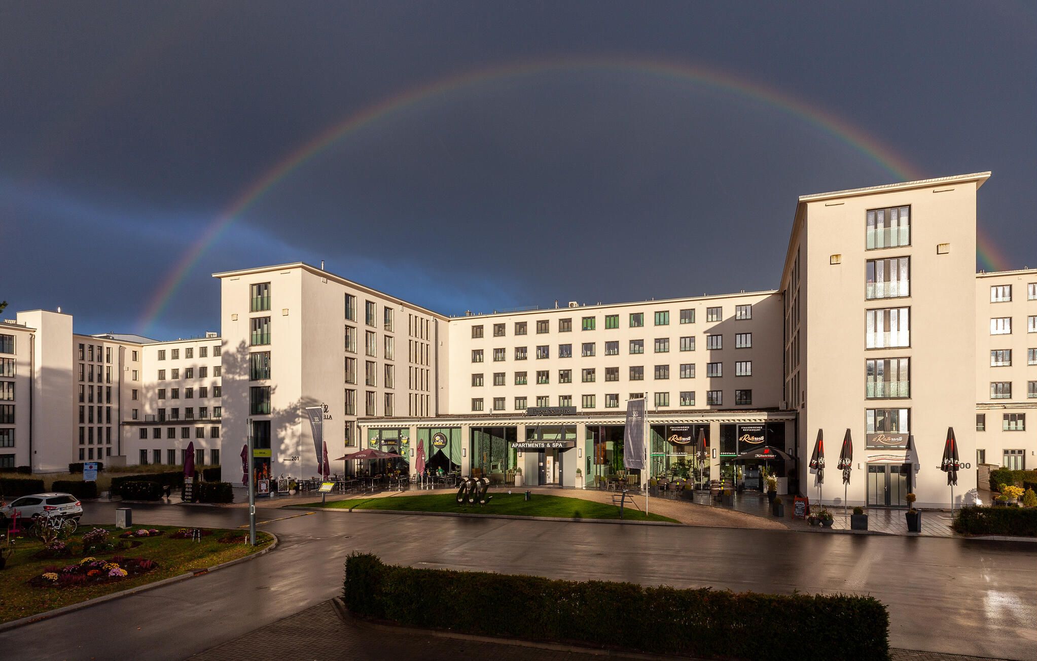 A multi-story hotel with a central courtyard, outdoor seating, and a visible sign for 'Apartments & Spa.'