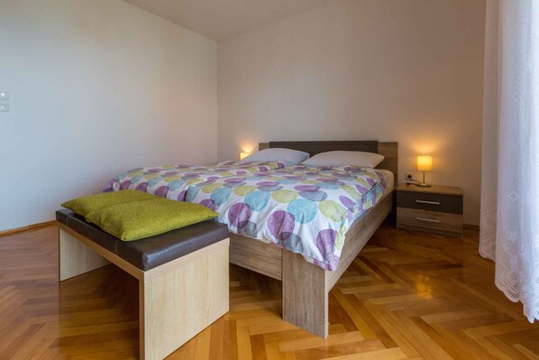 A bedroom with a bed, bedside tables, a bench, and a nightstand.