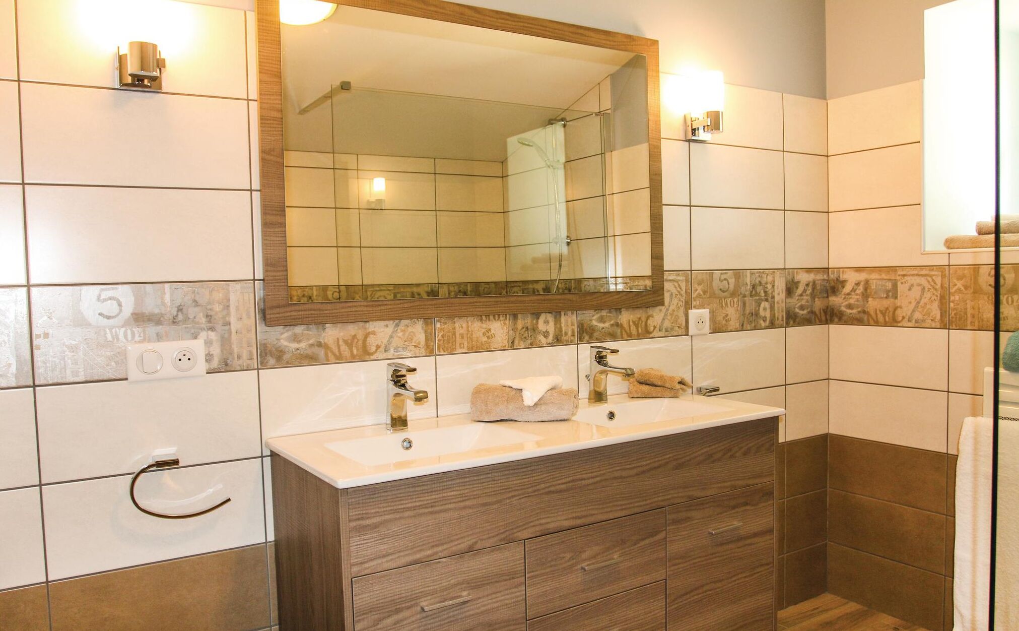 A bathroom with a wooden vanity, a mirror, and a shower area.