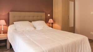 A neatly made bed with white linens, a wooden wardrobe, and two bedside lamps. - 2 bedroom stunning home in St Etienne de Boulogne (St Etienne de Boulogne)