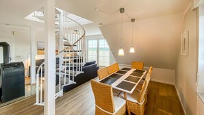Ein modernes Interieur mit Essbereich, Korbstühlen, einer Treppe und Blick ins Freie.