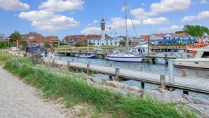 Ein Yachthafen mit vertäuten Booten, einem Leuchtturm und Wohnhäusern im Hintergrund.