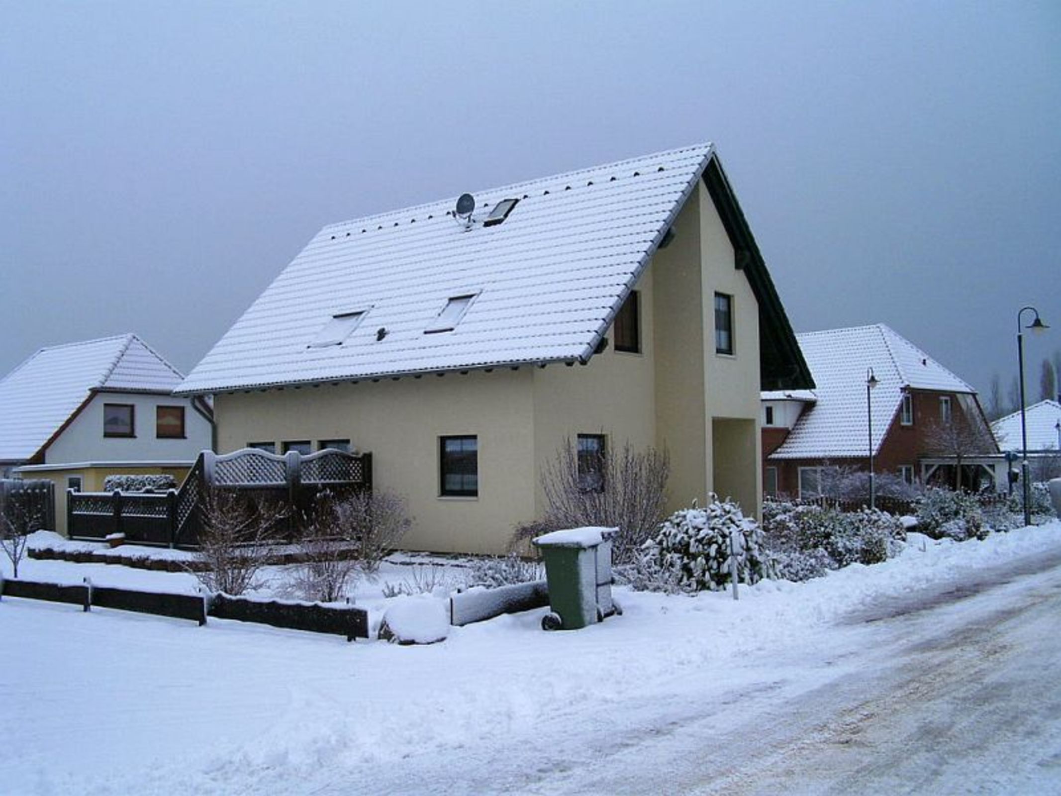 A residential building with a sloped roof, multiple windows, and a visible satellite dish.