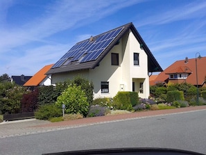 A house with solar panels on the roof, surrounded by greenery and a clear sky. - Rügen-Fewo 192 - Apartment (Glowe)