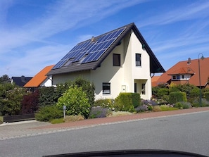 A house with solar panels on the roof, surrounded by greenery and a clear sky. - Rügen-Fewo 192 - Apartment (Glowe)