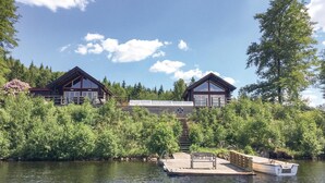 Une cabane avec un quai s’avançant dans un lac, entourée d’une végétation luxuriante.