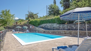 A swimming pool with stone flooring, surrounded by lounge chairs and umbrellas. - Lovely home in Dicomano FI with private swimming pool, can be inside or outside (Dicomano FI)