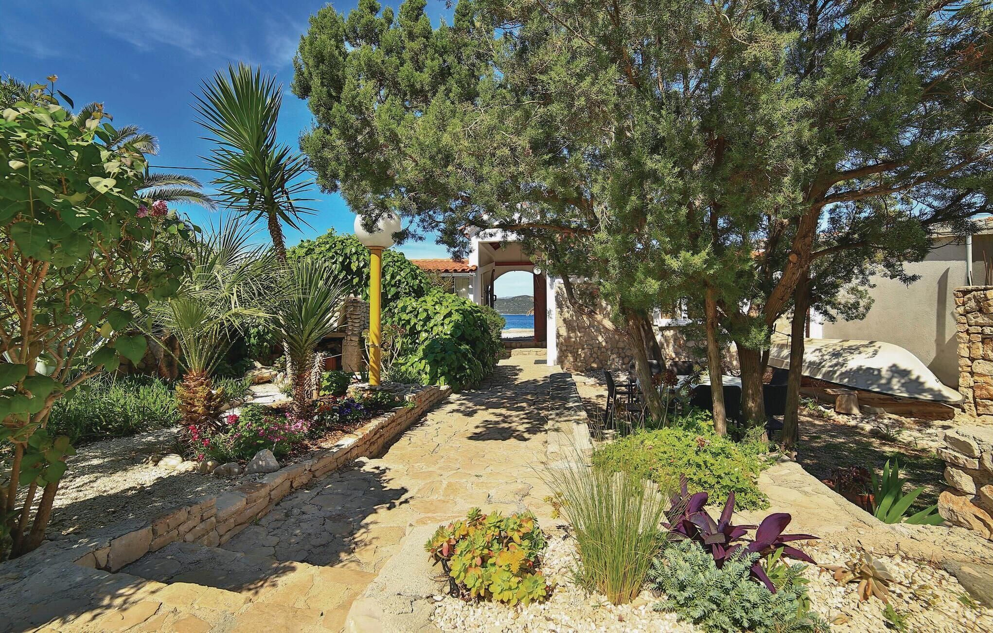 Un sentier de jardin menant à une arche en pierre, d’où l’on peut admirer la mer.