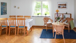 A dining area with wooden chairs and a table, a wicker chair, a lamp, and a view of greenery through a window. - Nice home in Urshult with WiFi (Urshult)