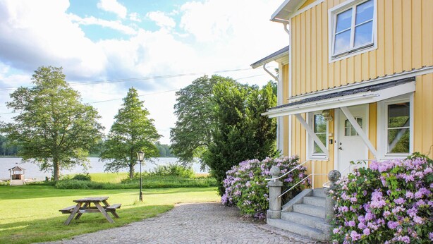 A yellow house with a paved driveway leading to a wooden picnic table and a stone staircase. - Nice home in Urshult with WiFi (Urshult)