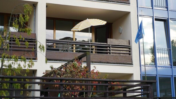 A modern building with a balcony, a striped umbrella, and a flag. - (57) 2-room apartment - apartment house Mecklenburg (Kühlungsborn)