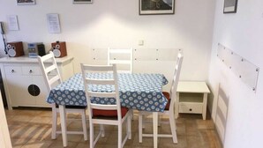 A small, clean room with a white table and chairs, a small cabinet, and a bed with a headboard. - (57) 2-room apartment - apartment house Mecklenburg (Kühlungsborn)