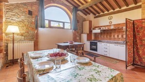 A rustic kitchen with stone walls, a dining area with a table set for four, and a window with a view. - Nice home in S.Vito In Monte TR (S.Vito In Monte TR)