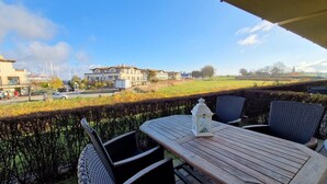 A patio with a table and chairs, overlooking a residential area with houses and a field. - (261) 2-room apartment-Hafenstraße - Apartment holiday dreams (Kühlungsborn)