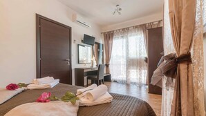 A hotel room with a bed, a desk, a chair, and a large window with curtains.