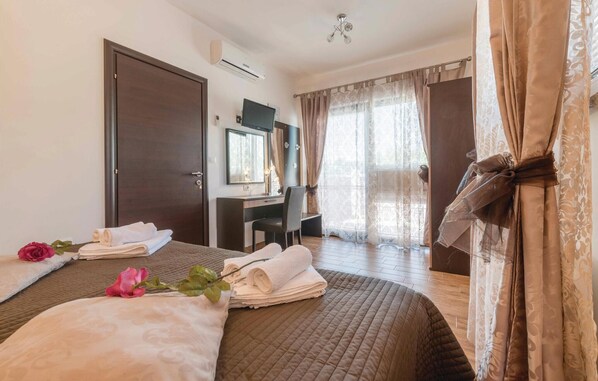 Une chambre d’hôtel avec un lit, un bureau, une chaise et une grande fenêtre avec des rideaux.