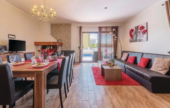 Una sala de estar moderna con comedor, chimenea, sofá y televisor.