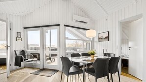 A modern dining area with a large table, black chairs, and a hanging light fixture. - Cozy home in Hvide Sande with sauna (Hvide Sande)