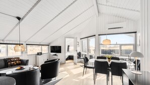 A spacious living area with a large TV, comfortable seating, and a dining area with a table and chairs. - Cozy home in Hvide Sande with sauna (Hvide Sande)