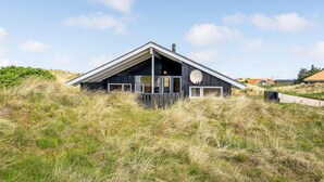 A modern house with a sloped roof, large windows, and a satellite dish. - Cozy home in Hvide Sande with sauna (Hvide Sande)