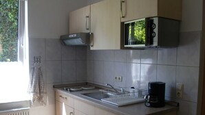 A small kitchen with a microwave, a coffee maker, and a dish rack. - Fw 1 - 69364 - FW1 - 69364 (Malchow)