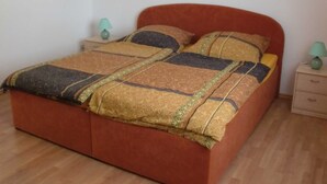 A bed with a patterned bedspread, two bedside tables with lamps, and a wooden floor. - Fw 1 - 69364 - FW1 - 69364 (Malchow)