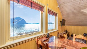 A wooden interior with a dining table and chairs, large windows with blinds, and a view of a lake and mountains. - Amazing home in Hundeidvik with ethernet internet (Hundeidvik)
