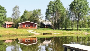A lakeside cabin with a dock and a small boat.