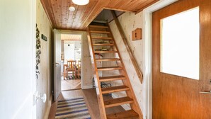 A wooden staircase leading to a second floor, a wooden door, and a hallway with a patterned rug.