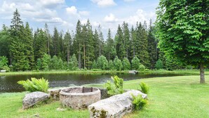 A lakeside setting with a fire pit, rocks, and a boat on the water.