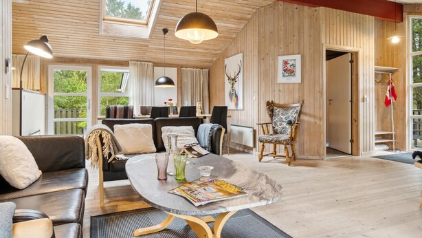 A cozy cabin interior with a round dining table, leather sofas, and a wooden dining table. - Awesome home in Brovst with sauna (Brovst)