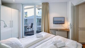 Une chambre d’hôtel équipée d’un lit, d’un bureau, d’une chaise, d’une télévision et offrant une vue sur le balcon extérieur.