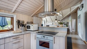 A modern kitchen with wooden cabinets, a built-in oven, a microwave, and a large stainless steel range hood. - Amazing home in Glesborg with sauna (Glesborg)