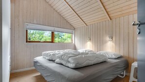 A bedroom with a bed, wooden walls, a window, and a thermostat. - Amazing home in Glesborg with sauna (Glesborg)
