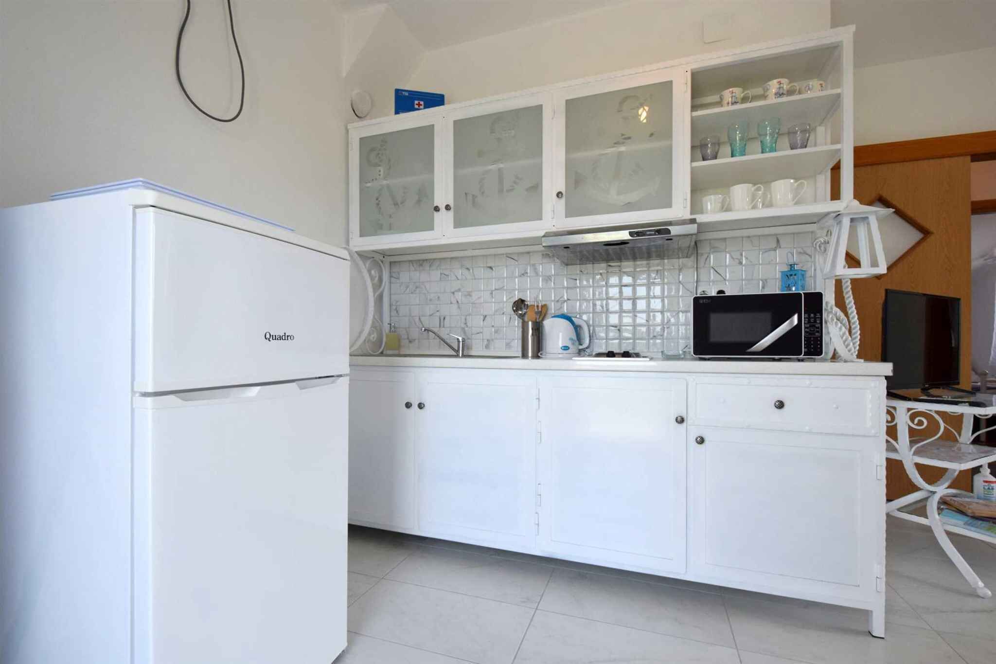 A kitchen with white cabinets, a microwave, and a coffee maker.