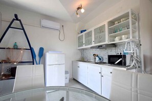 A kitchen with white cabinets, a refrigerator, a microwave, and a glass table.