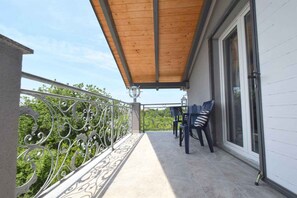 A balcony with a wooden ceiling, metal railing, and two chairs.