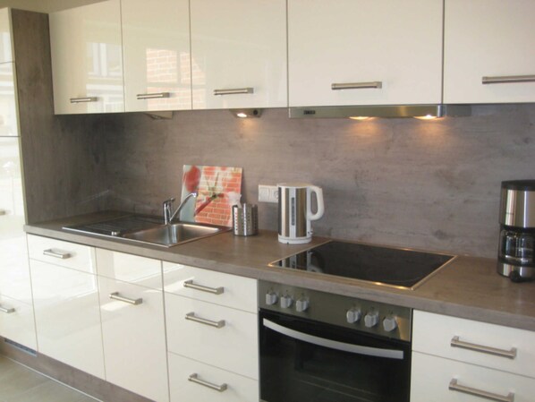 A modern kitchen with white cabinets, stainless steel appliances, and a tiled backsplash.